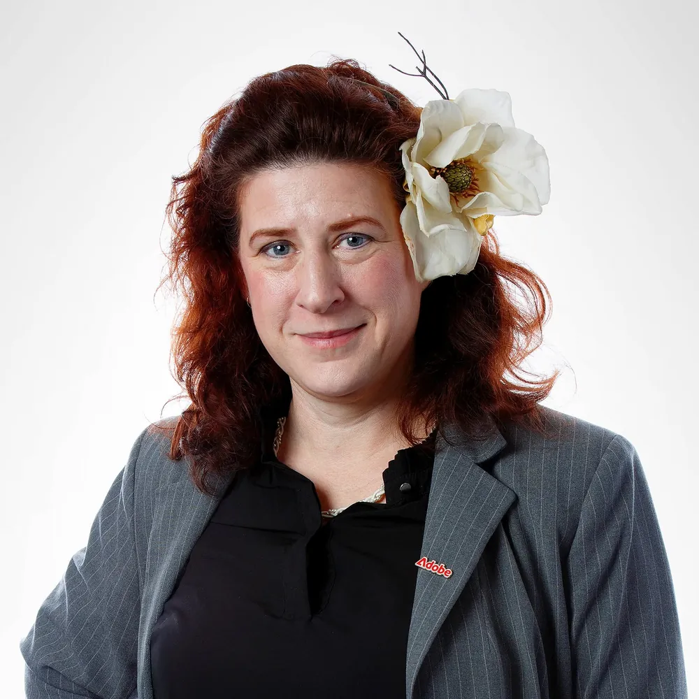 Mary Poplin in a grey pinstriped jacket with an Adobe pin and a white magnolia in her hair